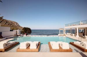 uma piscina com espreguiçadeiras e o oceano em Kantouni Beach Boutique Hotel em Panormos Kalymnos