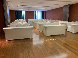 a conference room with white chairs and wooden floors at S&N Yiting Hotel Taizhou in Taizhou