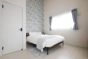 una camera bianca con un letto e una finestra di Hija on the Hill -SEVEN Hotels and Resorts- a Kunigami