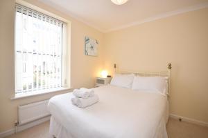ein Schlafzimmer mit einem weißen Bett und Handtüchern darauf in der Unterkunft Town or Country - Osborne House Apartments in Southampton