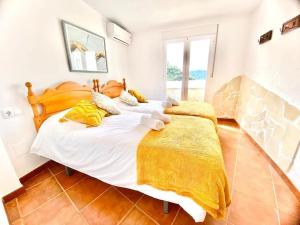 una camera da letto con un grande letto bianco con lenzuola gialle di Casa Rural Manantial de las Jaras a Istán