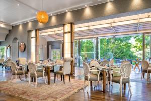 een eetkamer met tafels en stoelen en grote ramen bij Vineyard Hotel in Kaapstad