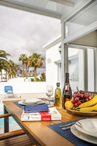 a table with a plate of fruit and a bottle of wine at Villa Nico by EscapeHome in Puerto del Carmen
