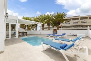 a swimming pool with lounge chairs and a hotel at Villa Nico by EscapeHome in Puerto del Carmen