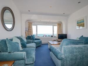 een woonkamer met blauwe meubels en een groot raam bij Sea View in Mevagissey