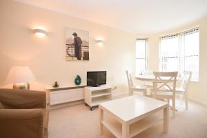 ein Wohnzimmer mit einem Tisch und einem TV in der Unterkunft Town or Country - Osborne House Apartments in Southampton