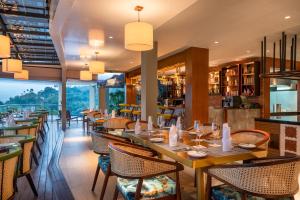 ein Restaurant mit Holztischen und -stühlen und einem großen Fenster in der Unterkunft Grand Serendib Hotel in Kandy