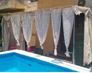 a blue swimming pool with curtains in front of a house at Cute home Zaros in Zarós