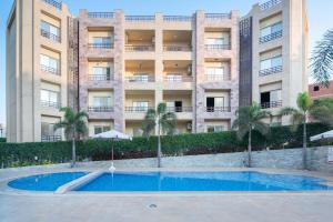 a hotel with a swimming pool in front of a building at New Cairo, Akoya Residence, Milena in New cairo