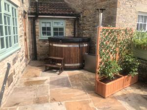 a patio with a hot tub and a bench next to a building at The Cottage Harmby in Spennithorne
