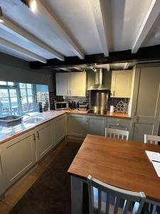 a kitchen with a wooden table with chairs and a counter at The Cottage Harmby in Spennithorne