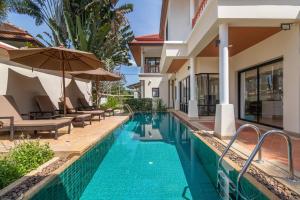 - une piscine à côté d'une maison avec un parasol dans l'établissement Laguna Fairway Villa, à Layan Beach