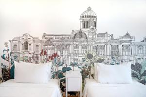 two beds in front of a mural of a building at Beat Hotel Bangkok in Bangkok