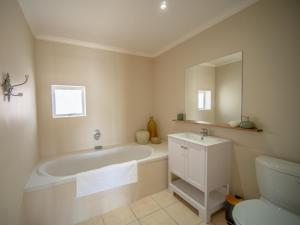 a bathroom with a tub and a toilet and a sink at 9 Quarter Deck in St Francis Bay