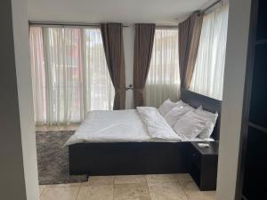 Una cama con sábanas blancas y almohadas en un dormitorio en Luxury @ the Garden en Accra