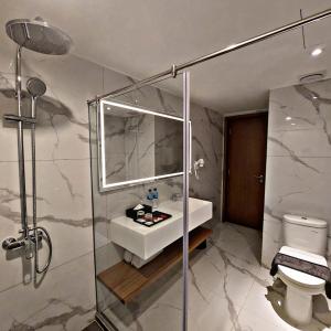 a bathroom with a sink and a shower and a toilet at Grand Zuri Pekanbaru in Pekanbaru