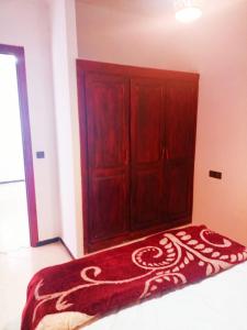 a bedroom with a red bed with a wooden cabinet at Hammadi's house in Oualidia