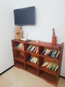 une étagère en bois remplie de livres et une télévision à écran plat. dans l'établissement Hammadi's house, à Oualidia
