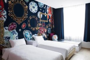 two beds in a room with a wall covered in plates at Beat Hotel Bangkok in Bangkok