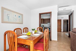 a dining room and kitchen with a wooden table and chairs at Villas Calan Bosch Olivia in Cala en Bosc