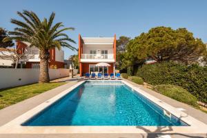 a villa with a swimming pool in front of a house at Villas Calan Bosch Emily in Cala'n Bosch