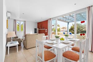 comedor y sala de estar con mesa blanca y sillas en Villas Calan Bosch Ona, en Cala'n Bosch