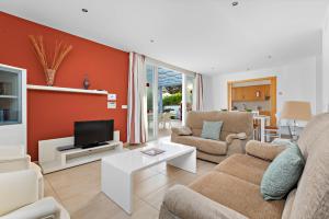 a living room with a couch and a tv at Villas Calan Bosch Ona in Cala'n Bosch