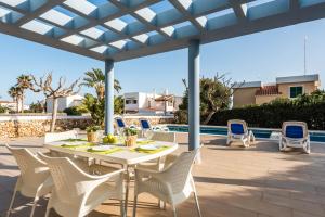 a patio with a table and chairs and a pool at Villas Calan Bosch Ona in Cala'n Bosch