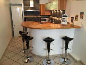 a kitchen with a counter with four black bar stools at Appartement Esterelle in Cassis