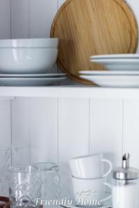 a shelf with white bowls and plates on it at Friendly Home - Einzelappartement "Pure" Köln Bonn Phantasialand in Brenig