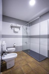 een badkamer met een toilet en een glazen douche bij Hostal Rio in Medellín