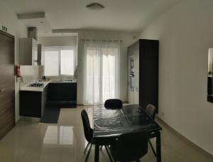 a kitchen with a glass table and chairs in it at Seron Apartment 3 in St. Paul's Bay