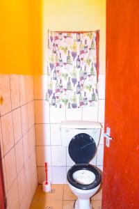 een badkamer met een toilet met een zwarte stoel en een raam bij Modern Cozy Studio House in Diani Beach