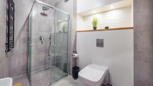 a bathroom with a glass shower and a toilet at Apartamenty Sun & Snow Nowe Hallerowo in Władysławowo