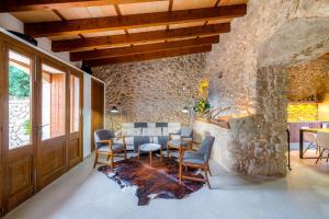a dining room with a table and chairs and a stone wall at Sa Serra in Sant Joan