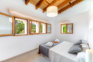 a white bedroom with a bed and windows at Sa Serra in Sant Joan
