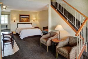 a hotel room with a bed and two chairs and a staircase at Lakeview Inns & Suites - Hinton in Hinton