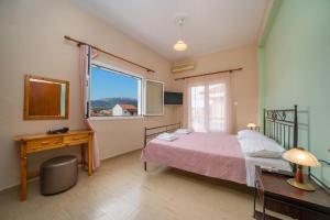 a bedroom with a bed and a desk and a window at Vasilakis Apartment in Sami