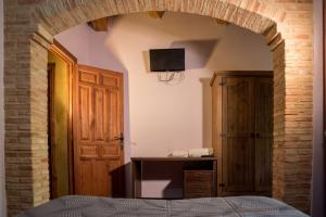 1 dormitorio con un arco con 1 cama y TV en Hospedaje Rural Casa Parri, en Poveda de la Sierra