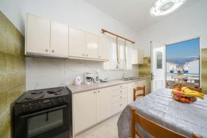 a kitchen with white cabinets and a table with a bowl of fruit at Vasilakis Apartment in Sami