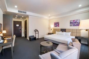 ein Hotelzimmer mit einem Bett, einem Tisch und Stühlen in der Unterkunft Ambassador Hotel in Bischkek