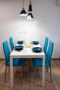 a white table with blue chairs and plates and wine glasses at Modern and Cozy 1BDR Apartment in the City Center in Sofia