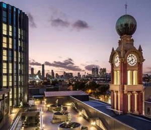 una torre dell'orologio in cima a un edificio con una città di The Sophia a Melbourne
