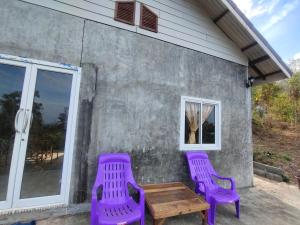 dos sillas púrpuras y una mesa de madera fuera de una casa en Lanta Farita House, en Phra Ae beach