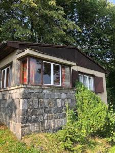 una pequeña casa de piedra en una colina con árboles en Retro chata na Čupku, en Metylovice