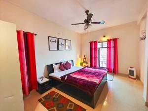 a bedroom with a bed with red curtains and a ceiling fan at Meraki - Entire 3BHK Villa With Himalayan Views in Rānīkhet