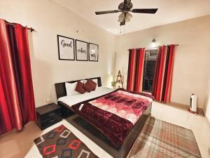 a bedroom with a bed with red curtains and a fan at Meraki - Entire 3BHK Villa With Himalayan Views in Rānīkhet