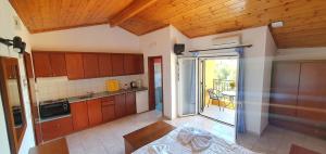 a kitchen with wooden cabinets and a balcony with a table at Villa Katerina in Agios Georgios Pagon
