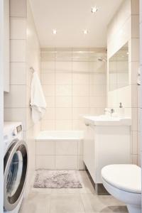 La salle de bains blanche est pourvue d'un lave-linge et d'un lavabo. dans l'établissement Grzybowska 16/22 by Homeprime, à Varsovie