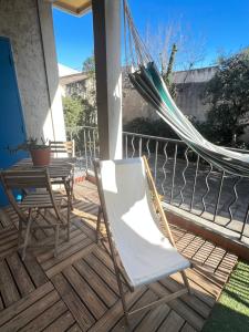 a hammock on a porch with two chairs and a table at Superbe appartement centre ville in Nîmes